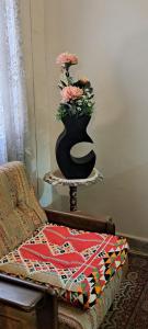 a black vase with pink flowers on a table at Free Pickup&Dropoff Cairo Airport limousine with staying at Hewidi Panorama Apartment 7Min to Airport & self checking in at anytime 免费利莫司汀往返机场 随时自助入住 شقة فاخرة تطل على مطار القاهرة مع توصيل مجاني in Cairo