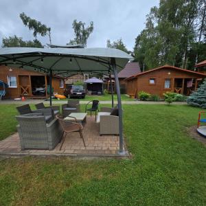 a patio with chairs and an umbrella in a yard at Domki letniskowe SOKÓŁ in Okuninka