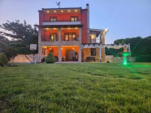 a large house with a green lawn in front of it at Villa Mariellie in Nea Peramos