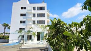 a white building with trees in front of it at NissiLant hotel & suites in Ayia Napa