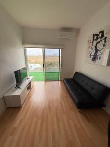 een woonkamer met een zwarte bank en een televisie bij bonito y acogedor apartamento in Famara