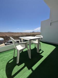 een witte tafel en een stoel op een balkon bij bonito y acogedor apartamento in Famara