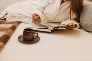 a woman reading a book with a cup of coffee at Glenoak Cottage in Sparkes Creek