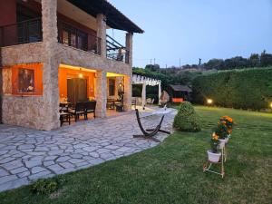 a house with a patio and a yard with flowers at Villa Mariellie in Nea Peramos