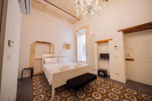 a bedroom with a white bed and a chandelier at La Pupa coi baffi - Edificio Storico in Centro in Conversano