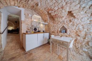 a kitchen with a table and a stone wall at La Pupa coi baffi - Edificio Storico in Centro in Conversano