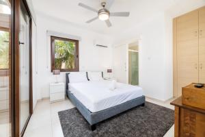 een witte slaapkamer met een bed en een plafondventilator bij Villa Enaria Serene 3Bdr Retreat in Ayia Thekla in Ayia Napa