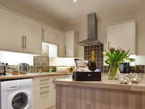 a kitchen with white cabinets and a dishwasher at Nether Cottage in Saline