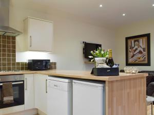 a kitchen with white cabinets and a counter with flowers on it at Nether Cottage in Saline
