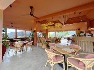 restauracja ze stołami, krzesłami i oknami w obiekcie Tebola Villa Resort w mieście Sidemen