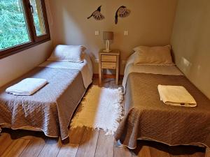 two beds sitting in a room with a window at Remanso del Bosque - Los Alerces Cabin in Villa La Angostura