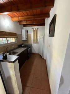 una cocina con fregadero y refrigerador en Las cabañas de Pascu, en Santa Rosa de Calamuchita