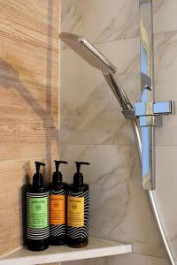 a group of four shampoo bottles sitting on a shelf next to a shower at Péra Skopelos - Mesa Sta Skalia in Skopelos Town
