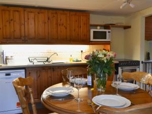 una cucina con tavolo in legno, piatti e bicchieri da vino di West End Cottage a Carrbridge