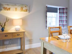 a dining room with a wooden table with a lamp and a window at Glebe Cottage in Urray