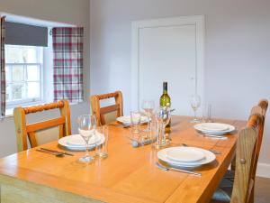 a dining room table with glasses and a bottle of wine at Glebe Cottage in Urray