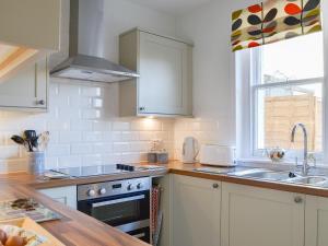 a kitchen with white cabinets and a sink and a stove at Glebe Cottage in Urray +6 photos