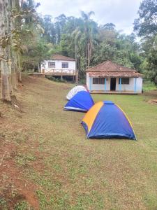 three tents in a field in front of a house at Recanto felicidade casa de vovó in Monte Sião