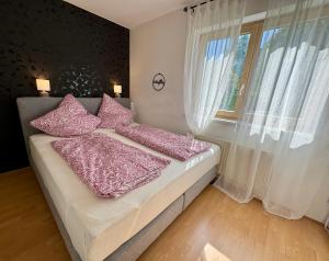 a bedroom with a bed with pink pillows and a window at Heimatliebe in Neunkirchen