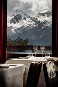 a table with two wine glasses and a view of a mountain at Hotel Chalet Il Capricorno in Sauze dʼOulx