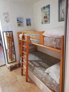 Zimmer mit 3 Etagenbetten und einem Spiegel in der Unterkunft Lucianasit in Cugnana Verde