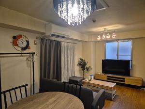 Una sala de estar con televisión y una mesa de comedor. en r311 Spacious Apartment near Dotonbori Namba Walk to Nipponbashi, en Osaka