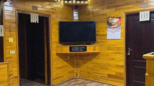 a television on a wall with a wooden wall at Sisi House Experience Hike & Batik Painting in Sa Pả