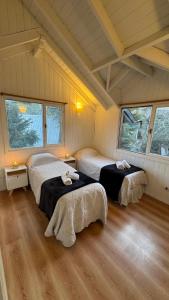 ein Schlafzimmer mit zwei Betten und zwei Fenstern in der Unterkunft Cabañas Los Cipreses- Pellín in San Martín de los Andes