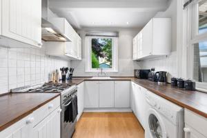 Una cocina con gabinetes blancos y un horno de estufa. en The Lynx Landing - Contractors - Free Parking - Near Harry Potter Studios, en Leavesden Green