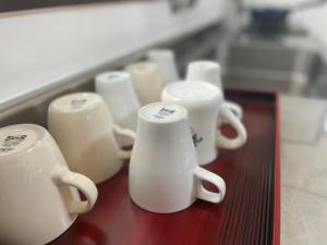 a row of white cups sitting on a counter at Nippori Osaka Nishi-Tengachaya Guesthouse西天下茶屋アパートメント in Osaka