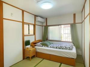 a bedroom with a bed in a room with a window at Nippori Osaka Nishi-Tengachaya Guesthouse西天下茶屋アパートメント in Osaka