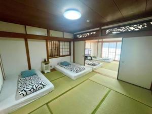 a room with two beds in a room with windows at Nippori Osaka Nishi-Tengachaya Guesthouse西天下茶屋アパートメント in Osaka