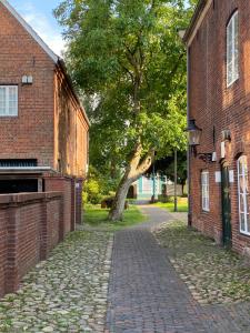 a cobblestone street between two brick buildings with a tree at Das Eulennest - Wohnen in historischem Ambiente in Brake