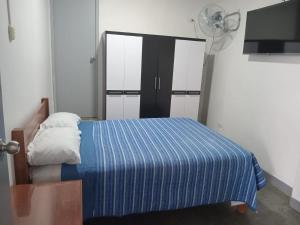 a bedroom with a bed with a blue blanket and a fan at kamelos Hospedaje in Paita