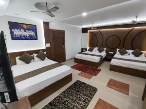a bedroom with two beds and a flat screen tv at Hotel Muskan in Mathura