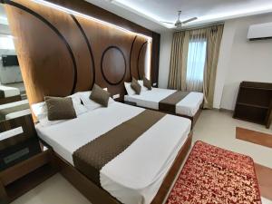 two beds in a hotel room with a large headboard at Hotel Muskan in Mathura +31 photos