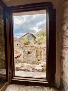 a window with a view of a stone building at Apartments Bella in Kotor +1 photo