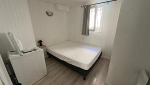 a small bedroom with a white bed and a window at L’appartement du Micocoulier in Salon-de-Provence