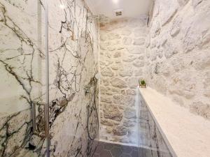 a shower in a room with a stone wall at NEW! Holiday Home Retro Stone House in Živogošće +30 photos