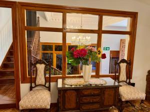a vase of flowers on a table with two chairs at Quinta El Escorial in El Escorial +51 photos
