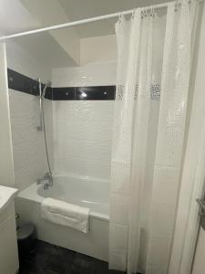 a white bathroom with a tub and a shower curtain at Studio Chaleureux in Neuilly-sur-Marne