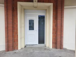 Appartement rez-de-chaussée في كارينتان: باب أبيض في مبنى من الطوب