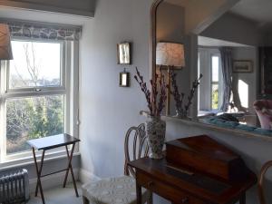 a living room with a table and a mirror at Gaerwen in Criccieth