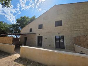 un grand bâtiment en pierre avec des portes vitrées dans l'établissement Domaine de la Tapie de Bouchet - en Camargue, à Arles