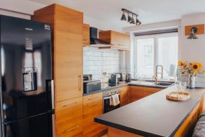 a kitchen with wooden cabinets and a black refrigerator at Central Manchester Gem with Stylish 2BR Retreat and Free Carpark in Manchester +37 photos