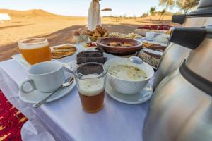 a table with food and drinks on a table in the desert at Nour Luxury Camp in Merzouga +11 photos