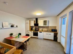 a kitchen with white cabinets and a wooden table at LüttelHome, moderne Ferienwohnung im Grünen mit Highspeed-Glasfaser in Brüggen