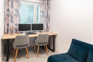 a desk with a computer and two chairs in a room at Po Sąsiedzku Apartament z Klimatem in Włocławek