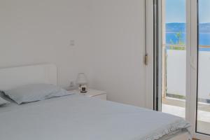 a white bedroom with a bed and a balcony at Casa Moderna - New Spacious Apartments in Lokva Rogoznica