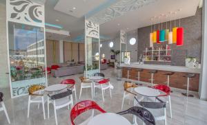a restaurant with white tables and red chairs at Nicholas Color Hotel in Ayia Napa